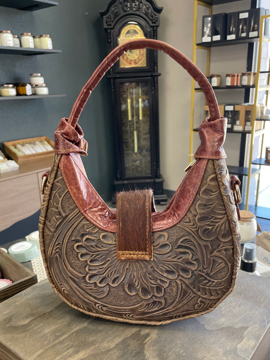 Decorative leather bag with intricate patterns on a blurred background