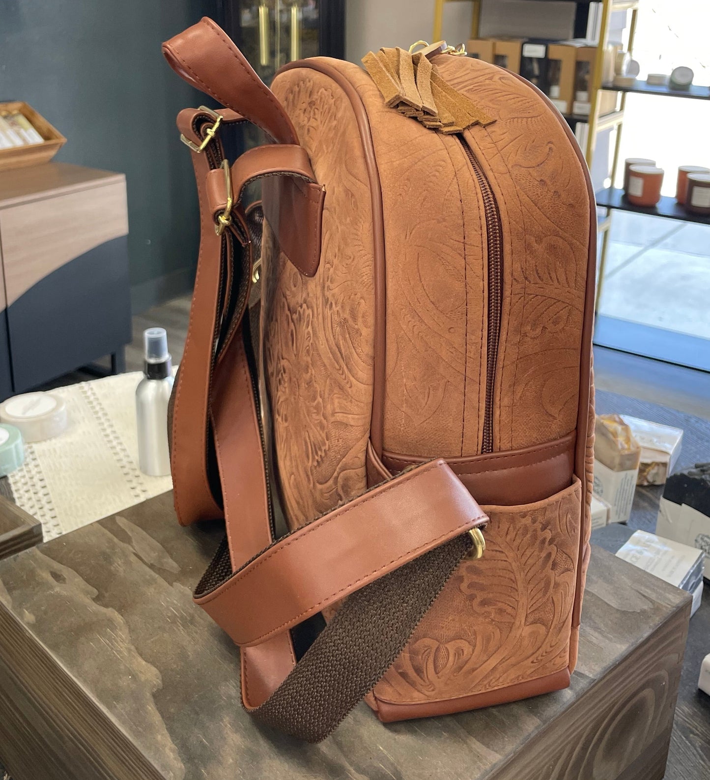 Brown leather backpack on a wooden surface with a store interior in the background