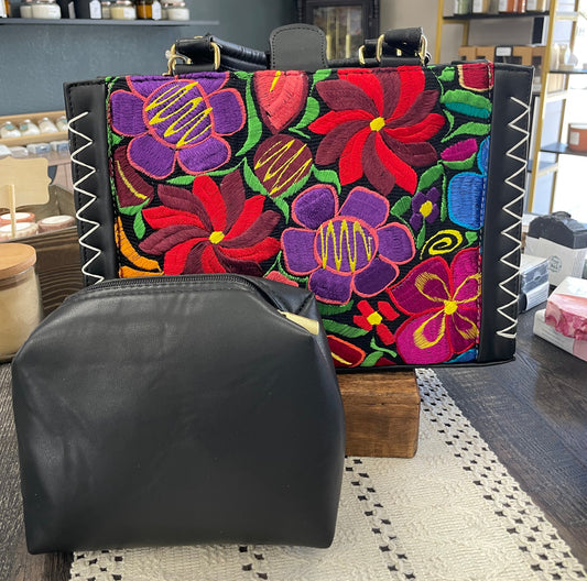 Colorful floral-patterned handbag with black accents in a room setting.