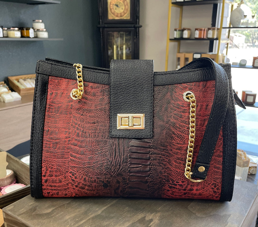 Red and black handbag with gold accents on a counter in a store setting