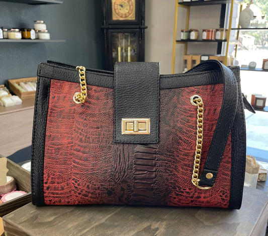 Red and black handbag with gold accents on a counter in a store setting